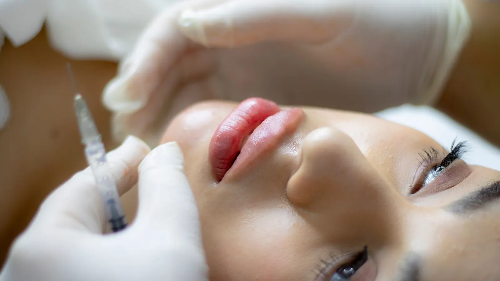Profesional aplicando un tratamiento de estética facial con jeringuilla
